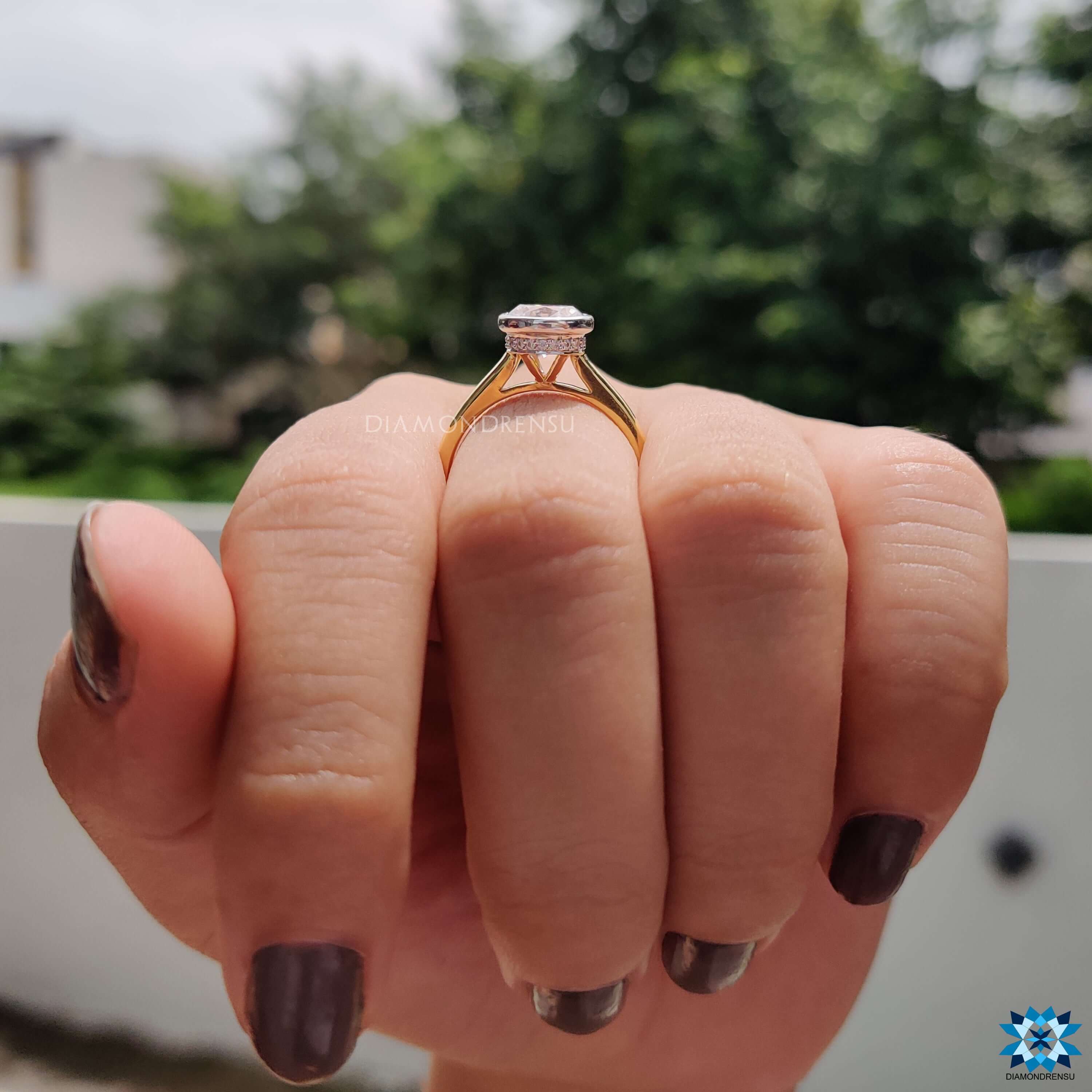 Yellow gold moissanite ring with bezel and prong details.
