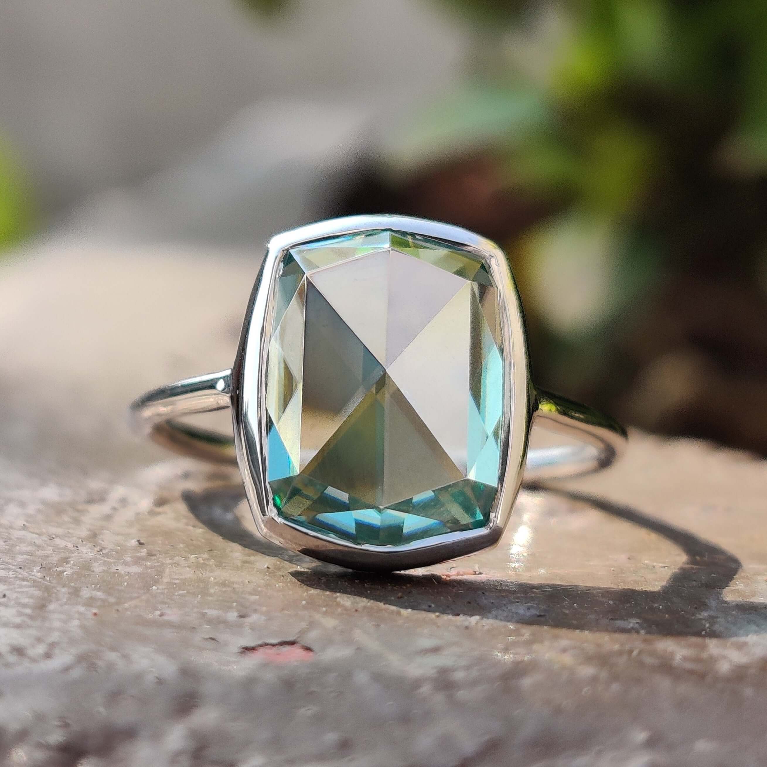 Cyan blue cushion rose cut moissanite ring in a white gold bezel setting.