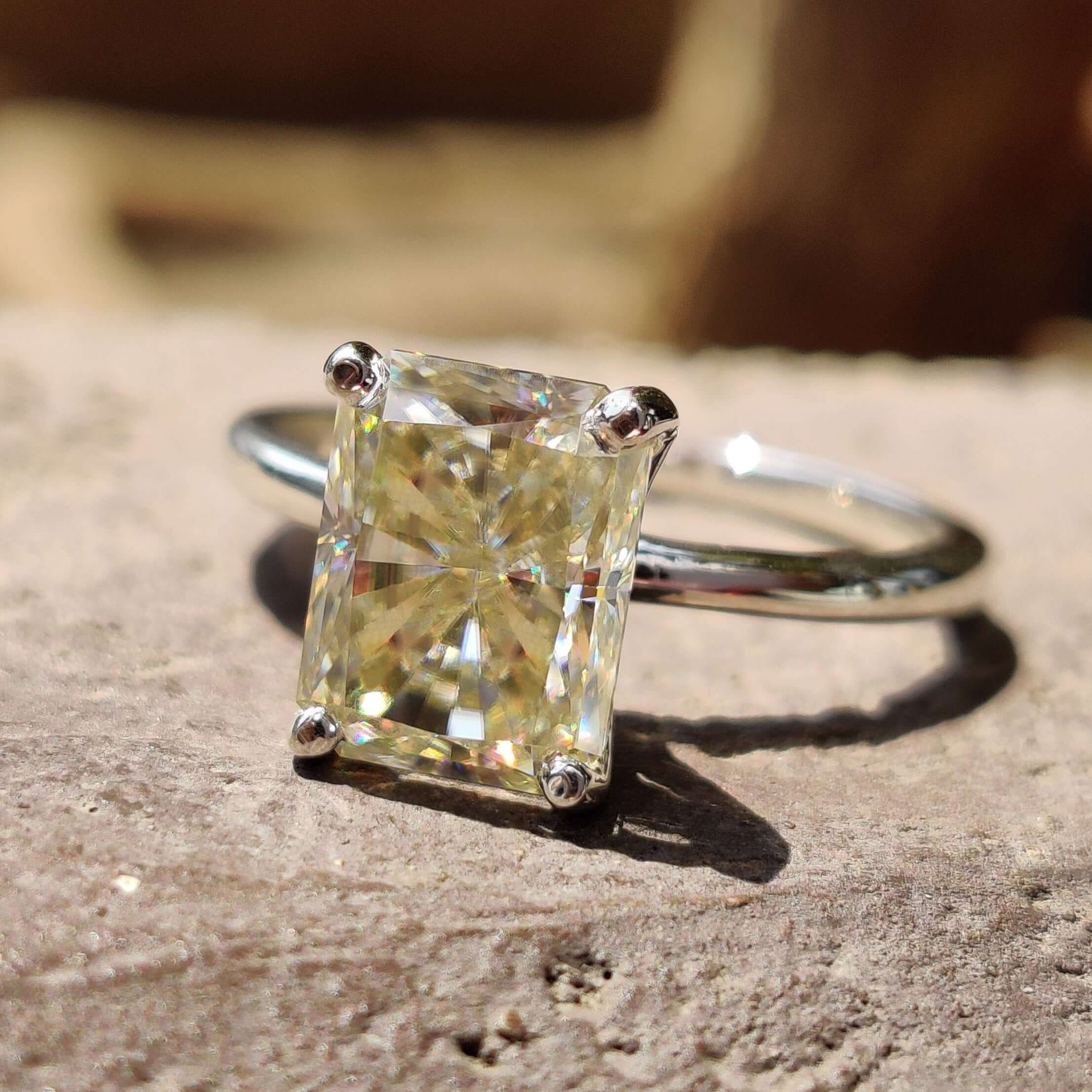 Light yellow engagement ring with radiant cut moissanite in a solitaire setting crafted in white gold ring.