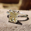 Light yellow engagement ring with radiant cut moissanite in a solitaire setting crafted in white gold ring.