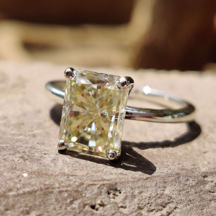 Light yellow engagement ring with radiant cut moissanite in a solitaire setting crafted in white gold ring.