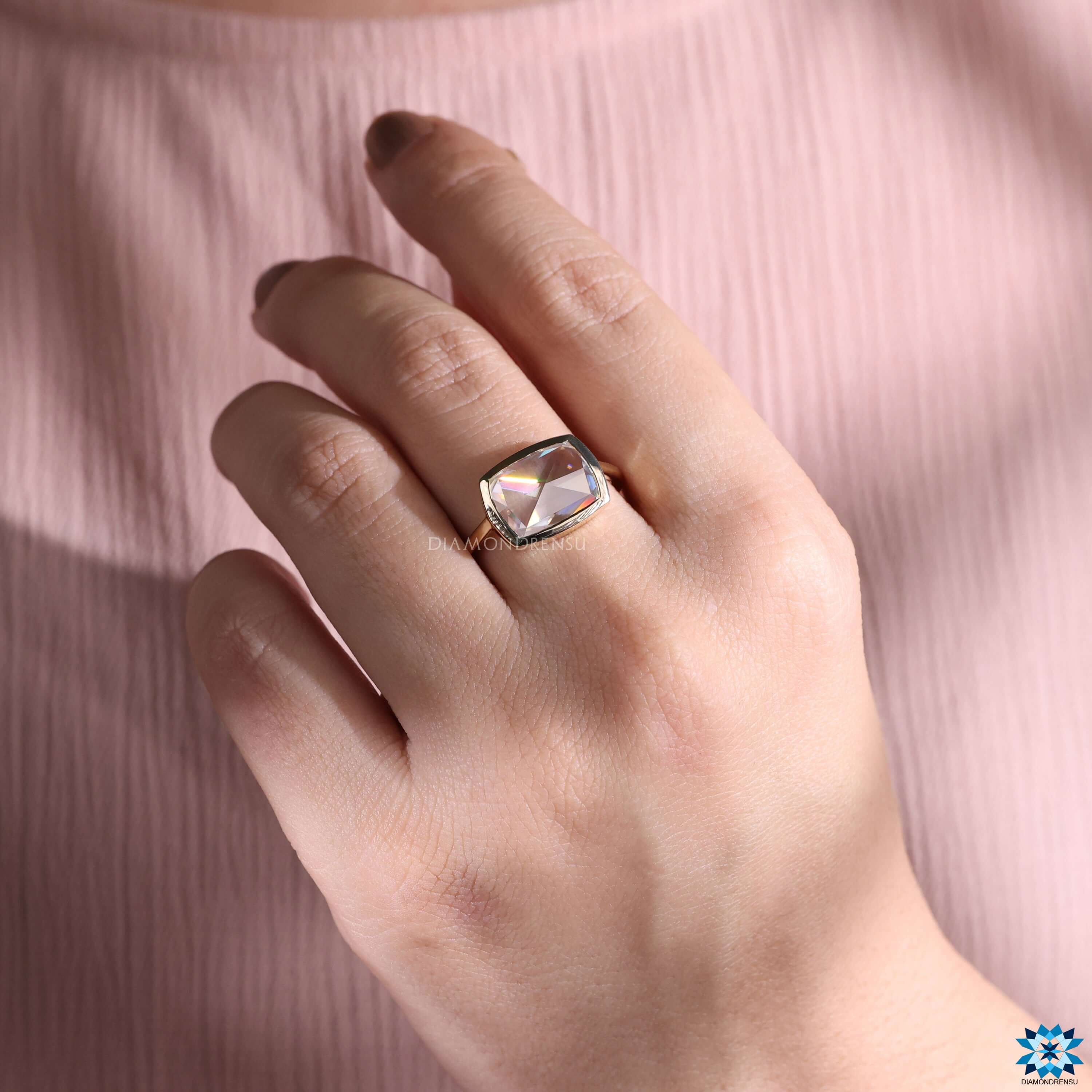 Cushion cut ring in yellow gold with bezel setting.