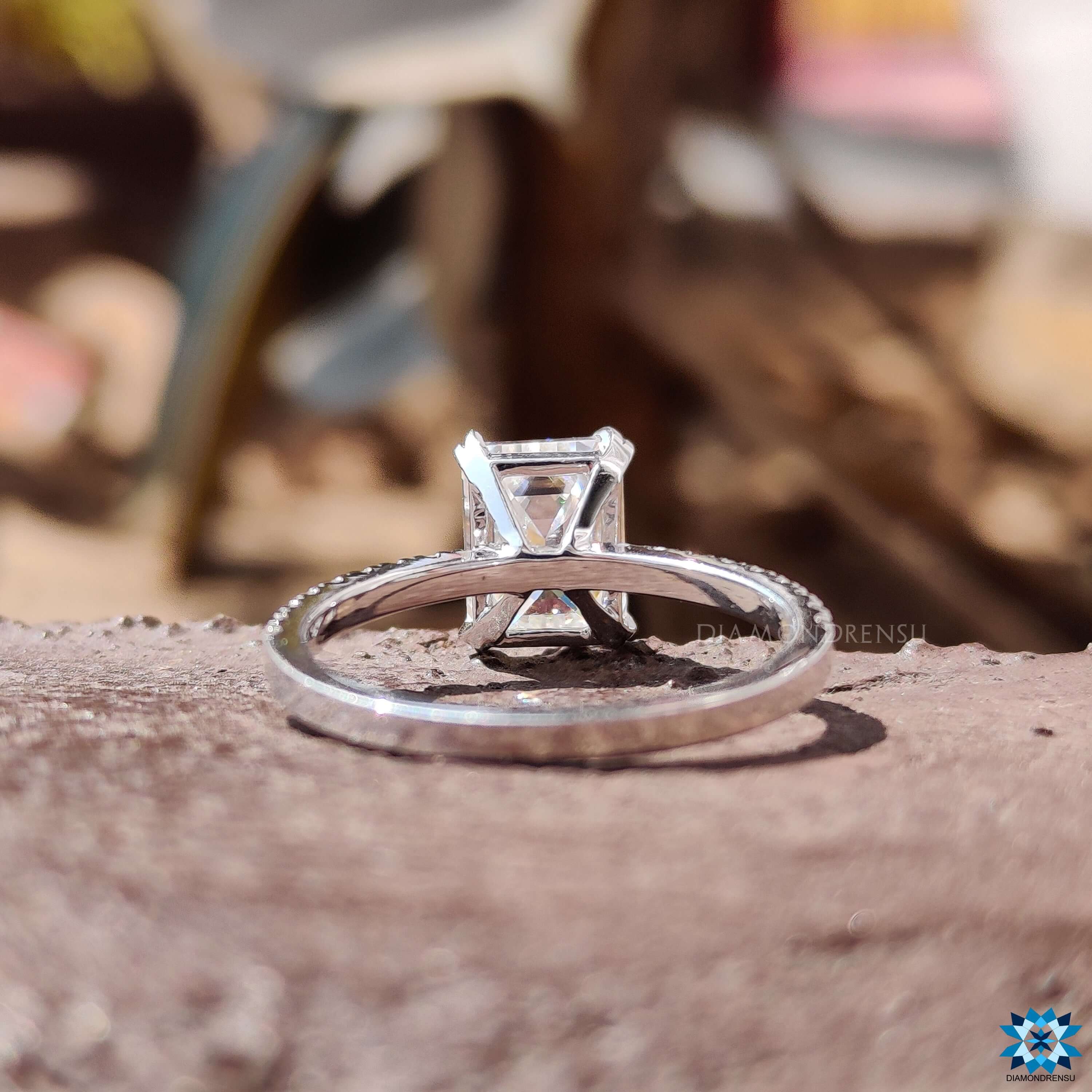 Custom white gold ring featuring emerald cut moissanite and pave details.