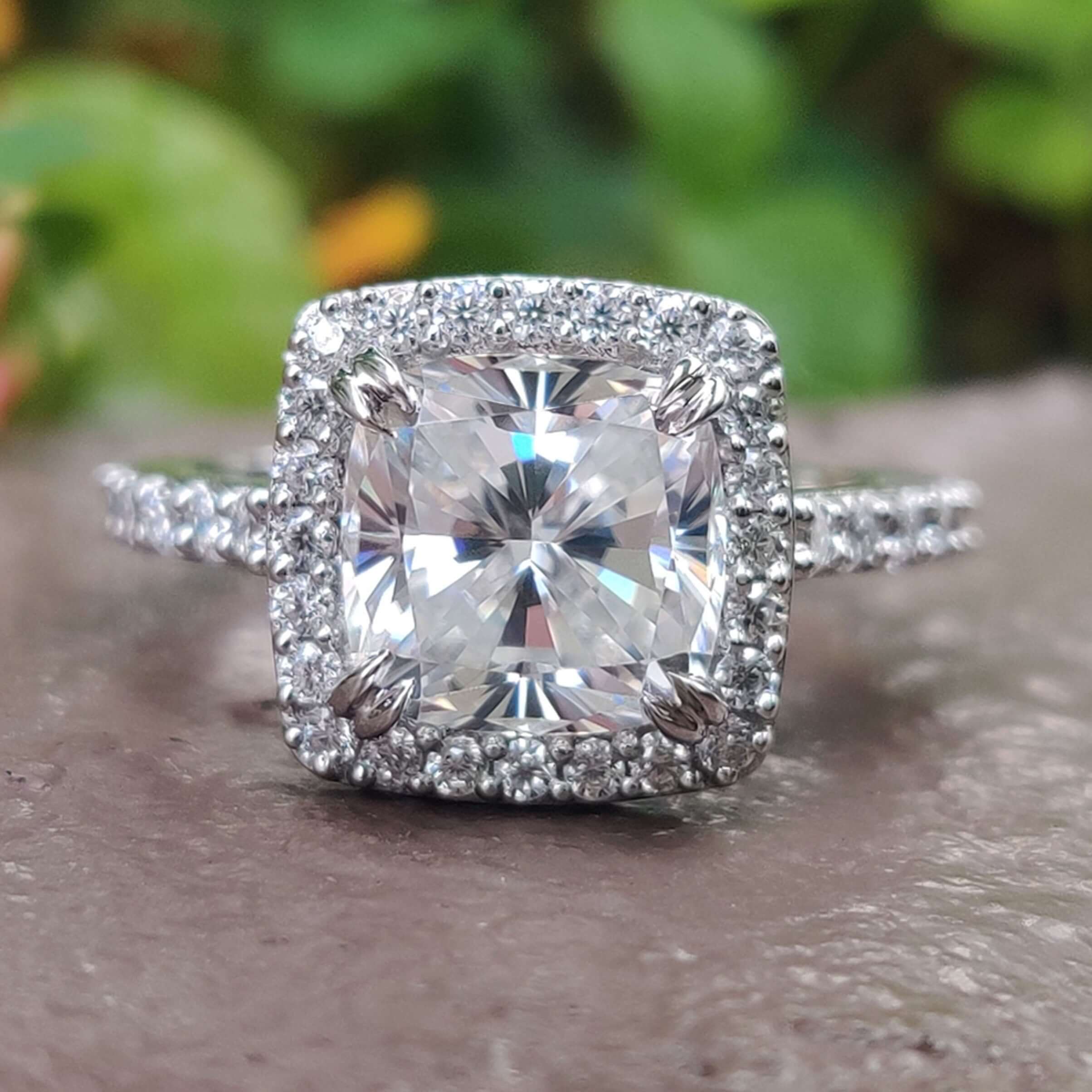 Cushion cut moissanite ring with halo and pavé band.
