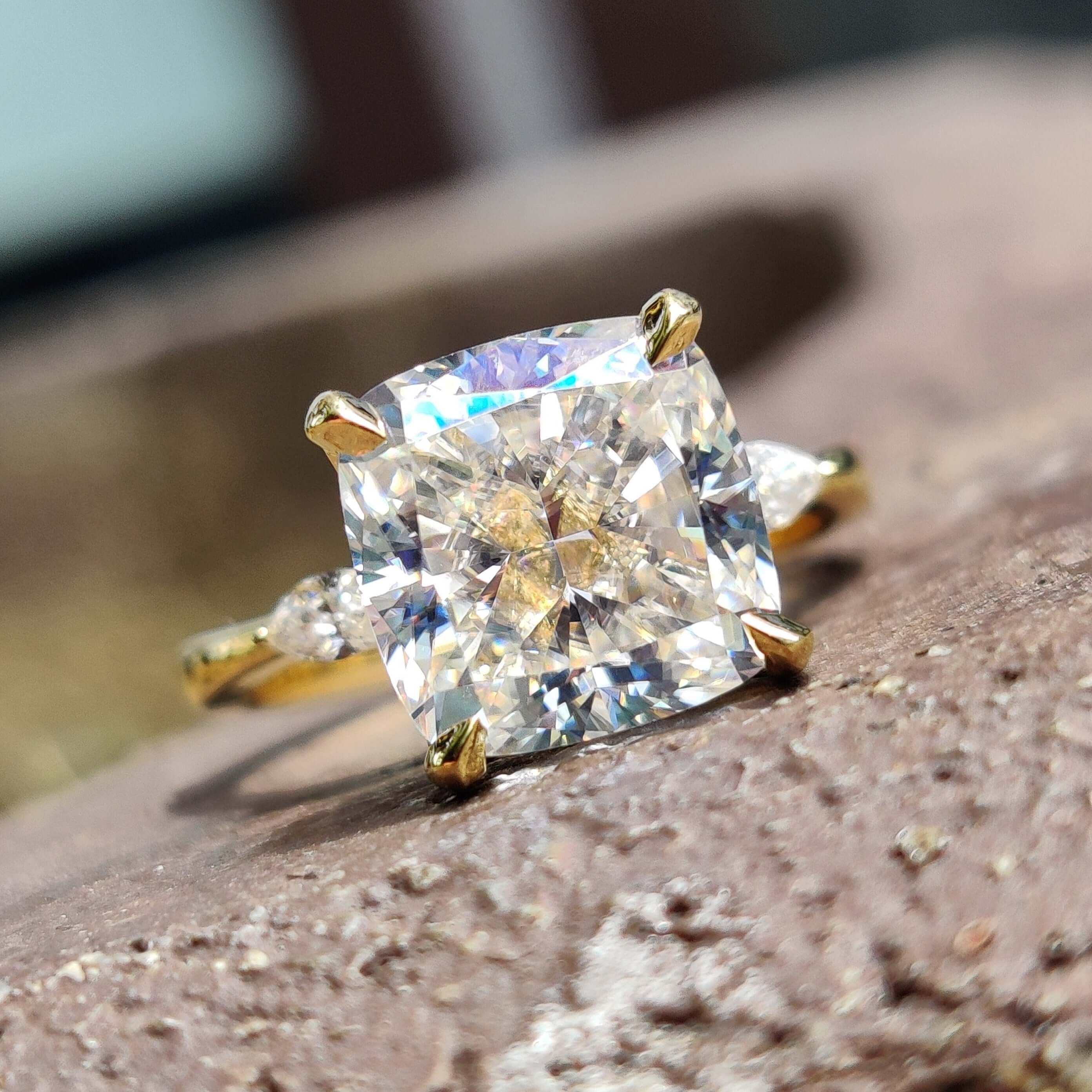 Moissanite three stone engagement ring with cushion cut centre and two pear side stones.