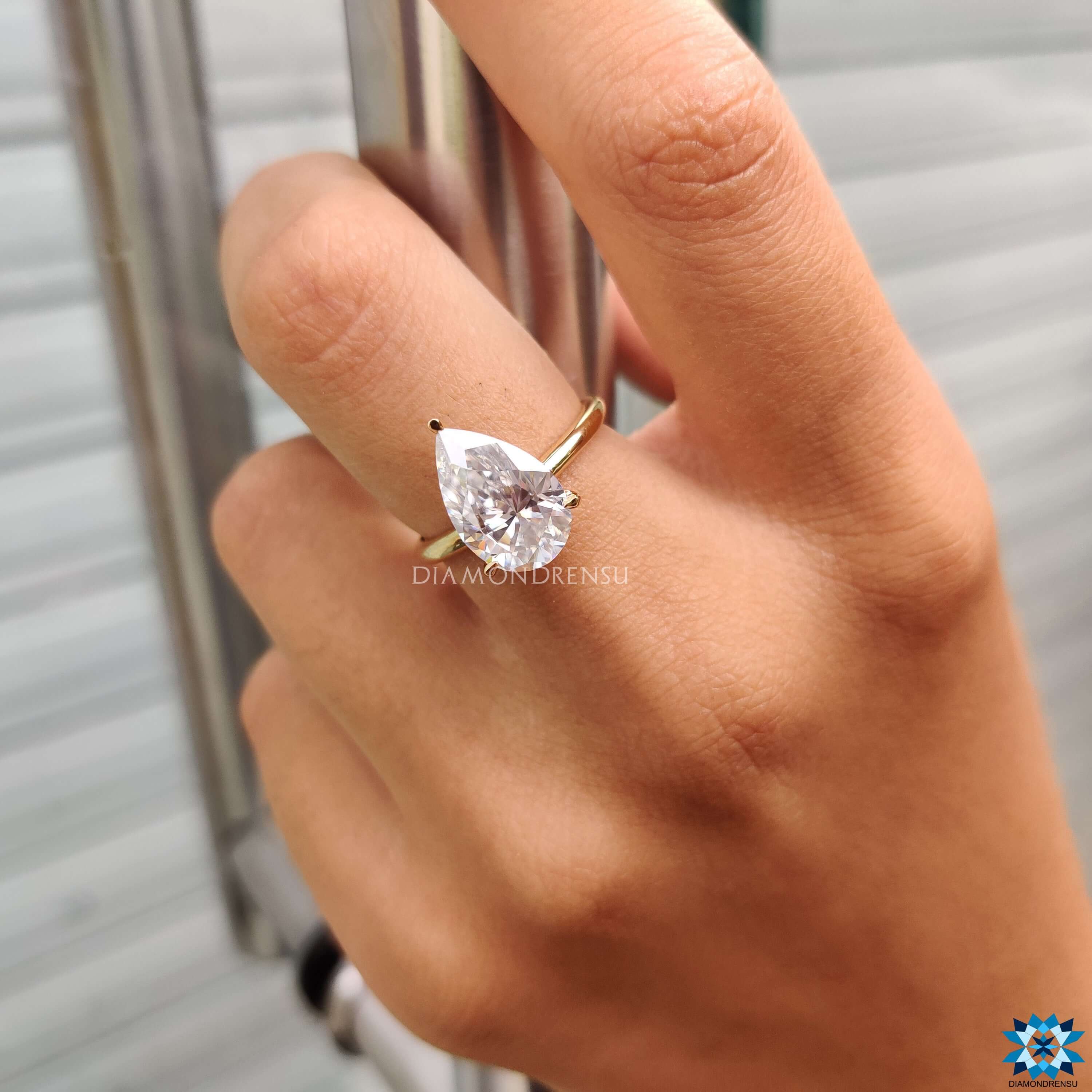 Yellow gold engagement ring with pear moissanite center.