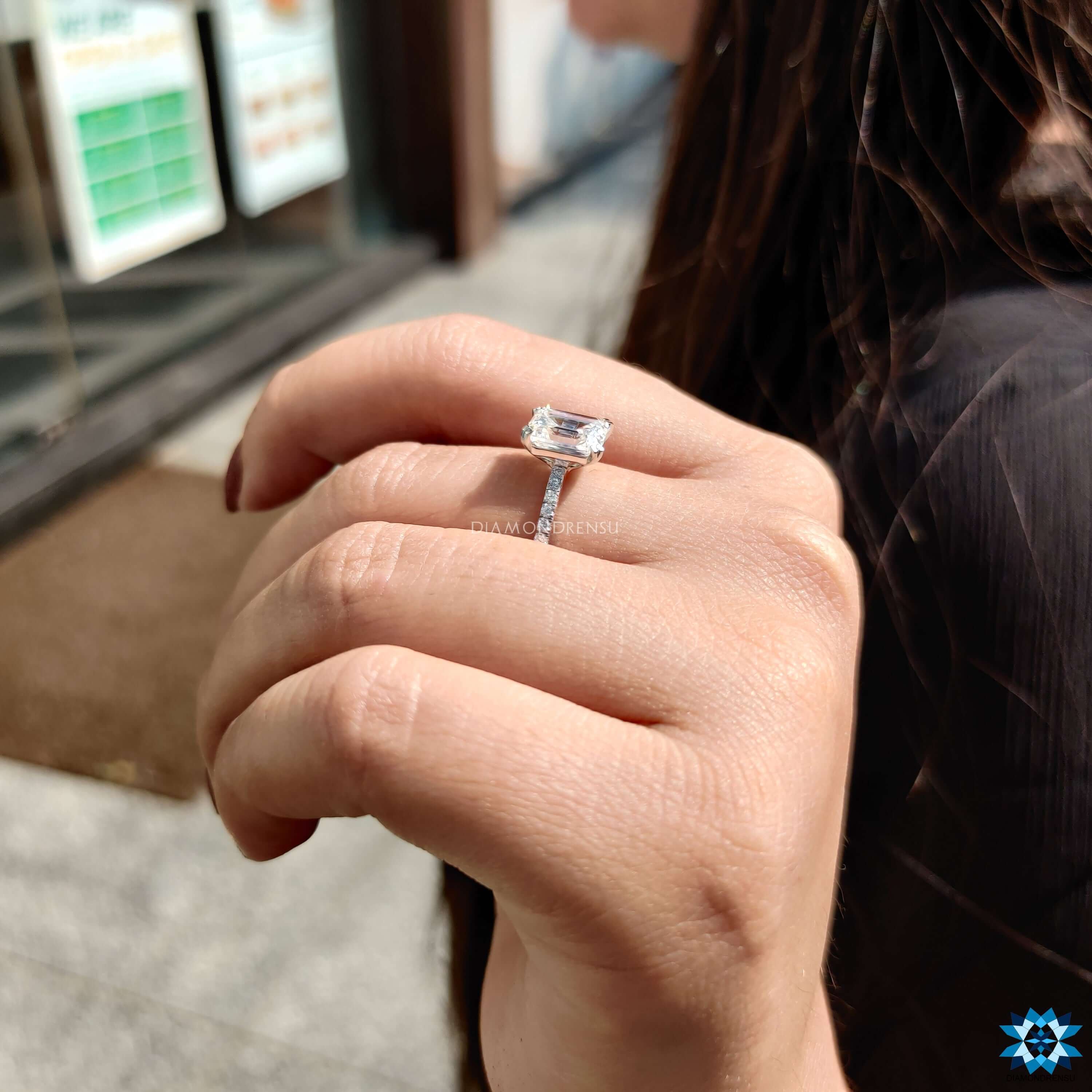 Pave setting moissanite engagement ring with emerald cut center stone.