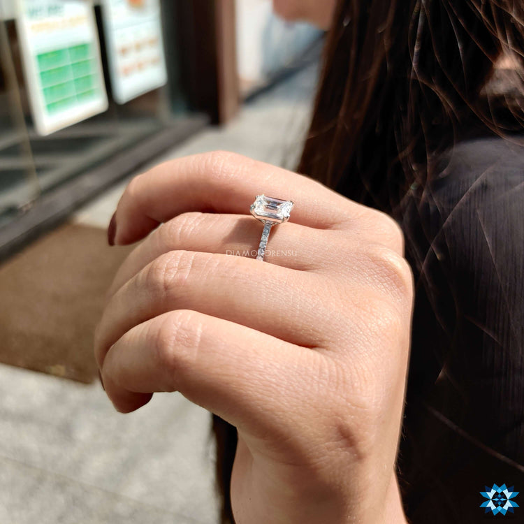 Pave setting moissanite engagement ring with emerald cut center stone.