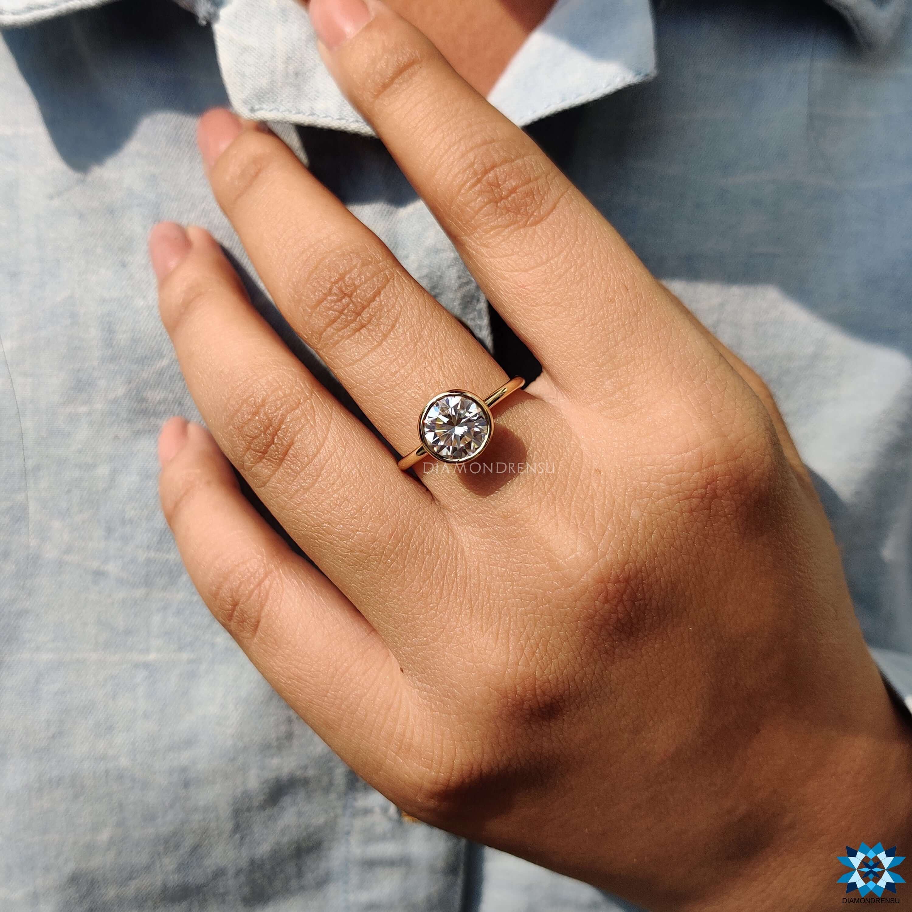 Handmade engagement ring featuring a round bezel moissanite.
