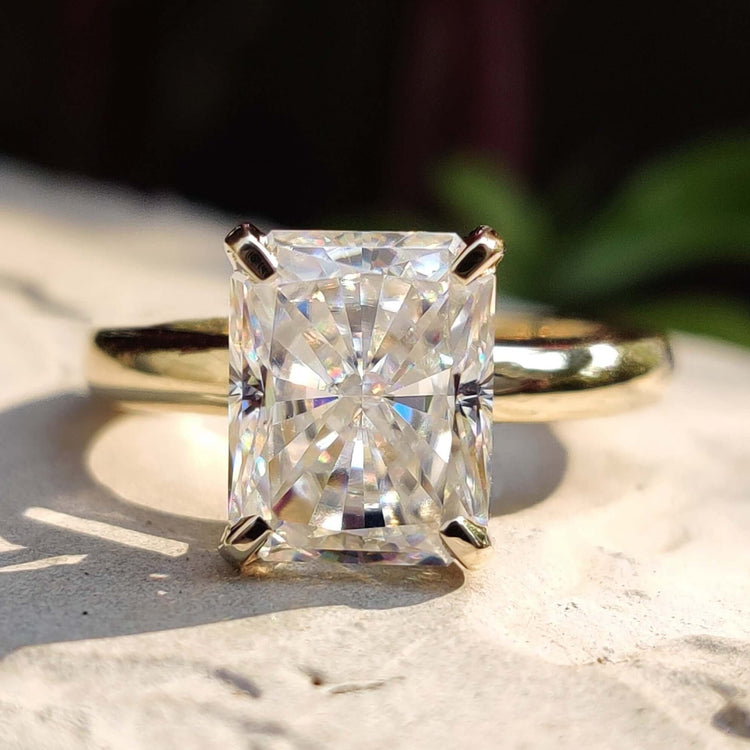 Radiant cut moissanite solitaire ring set in yellow gold.
