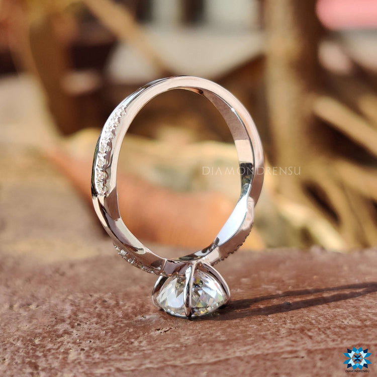 Round moissanite engagement ring with twisted band design and custom setting.
