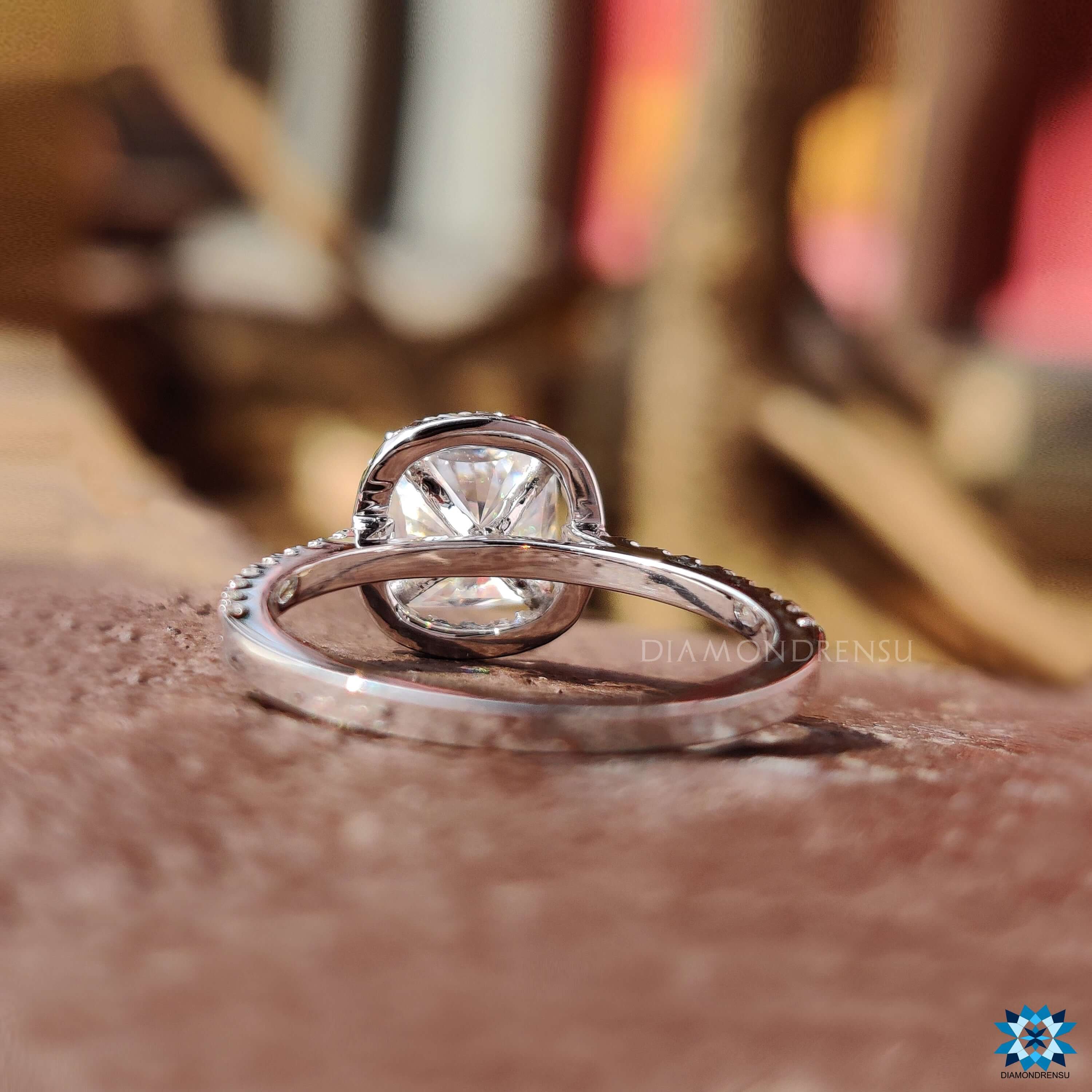 Halo engagement ring featuring cushion moissanite and round accents.