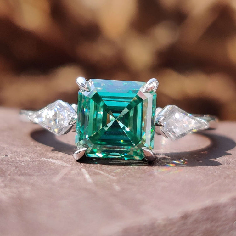 Asscher cut ring with green moissanite center stone.