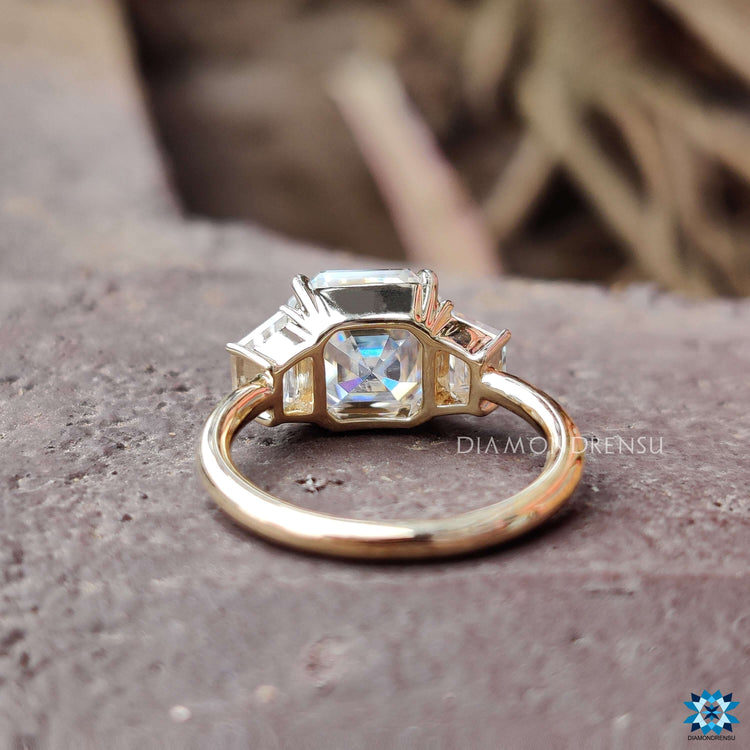 Custom engagement ring with asscher center and step-cut side stones.