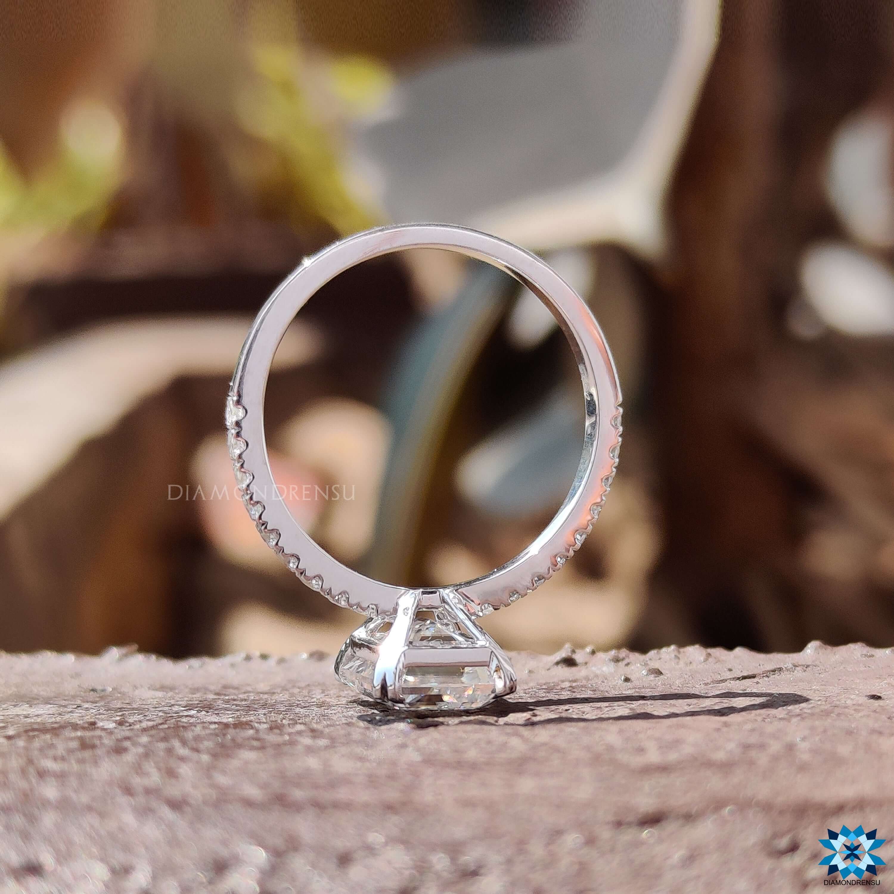 White gold ring showcasing emerald step cut moissanite and handcrafted pave band.
