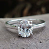 Oval moissanite engagement ring with a 4 round prong set in a white gold cathedral setting.