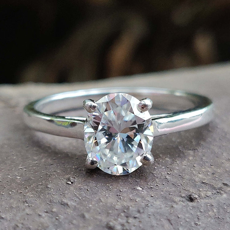 Oval moissanite engagement ring with a 4 round prong set in a white gold cathedral setting.