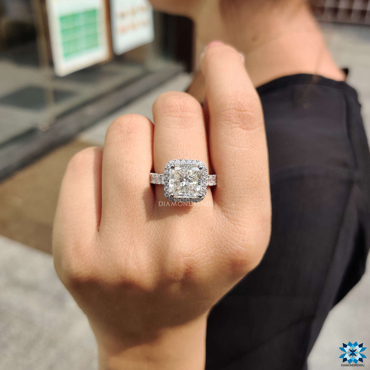White gold radiant cut ring with pave halo and prong mount.