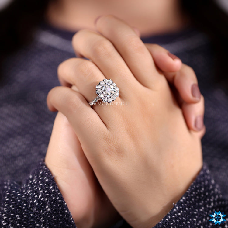 White gold ring featuring halo setting and round cut moissanite details.