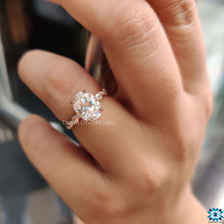 Twisted rose gold ring featuring oval cut moissanite and under halo.