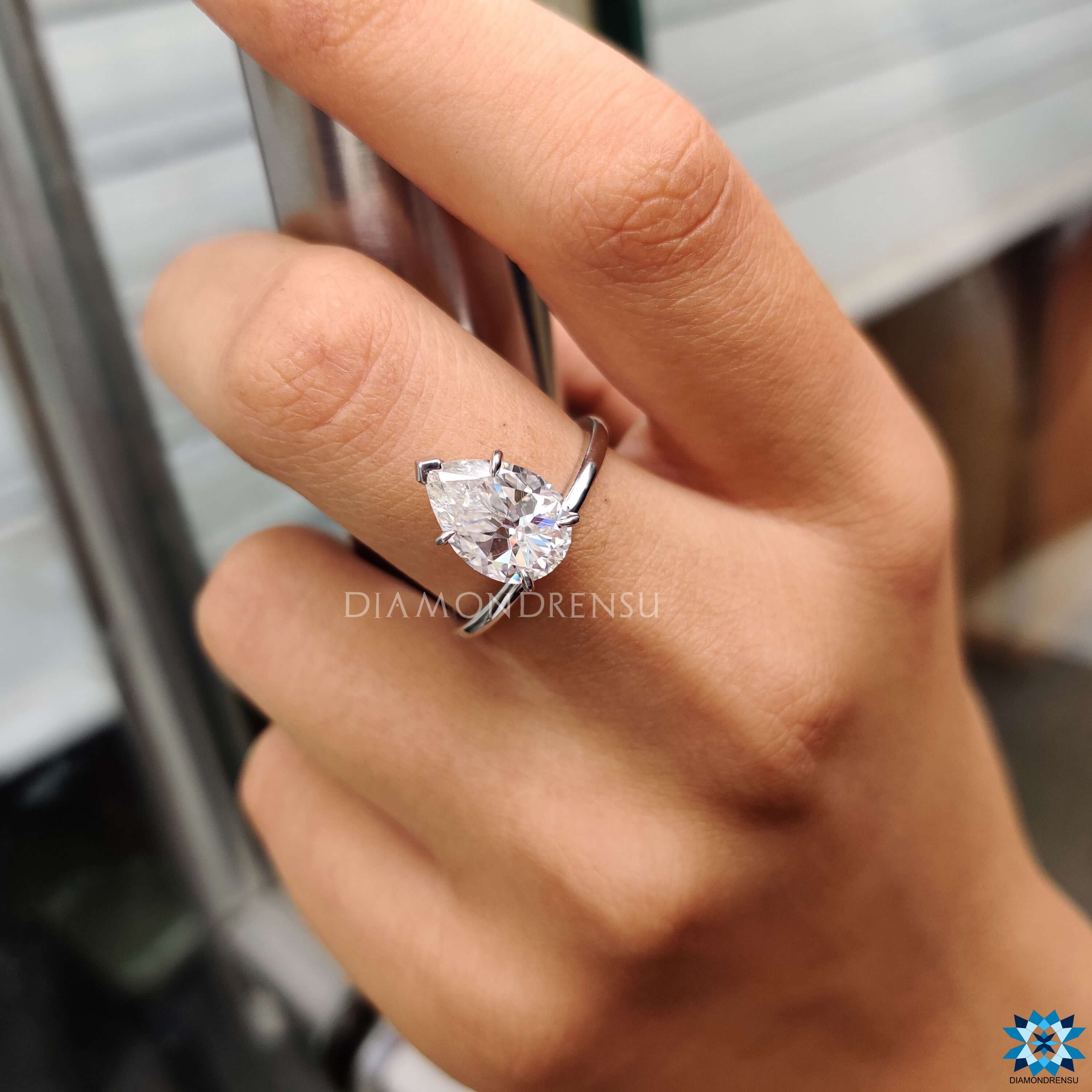 Custom engagement ring featuring upside down pear moissanite in solitaire style.