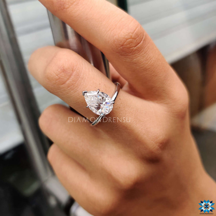 Custom engagement ring featuring upside down pear moissanite in solitaire style.