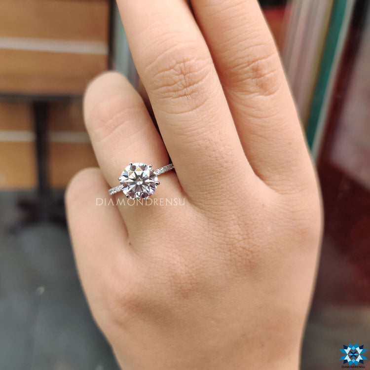 White gold engagement ring with round moissanite and pave band.