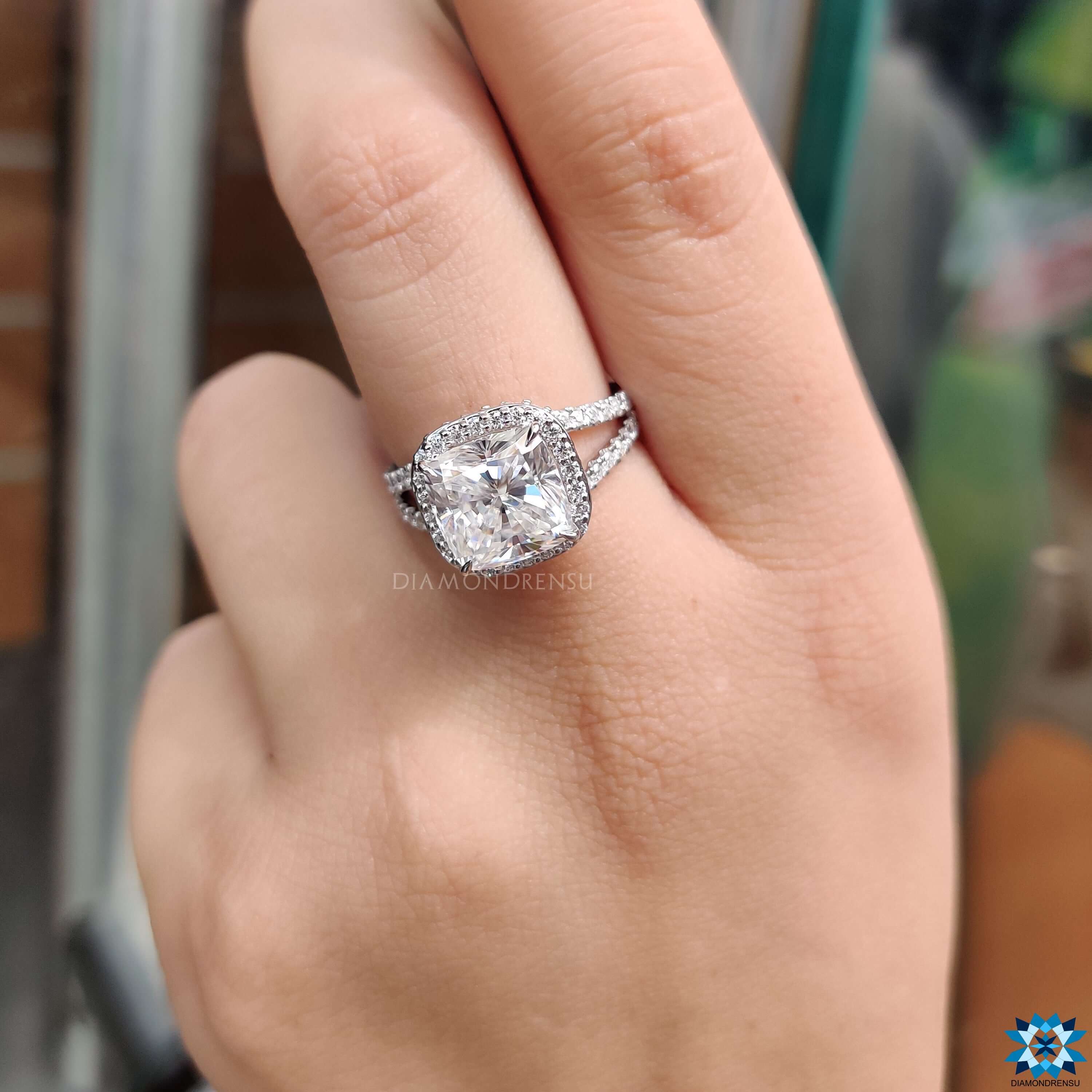 Round cut side stones enhance cushion cut moissanite ring.