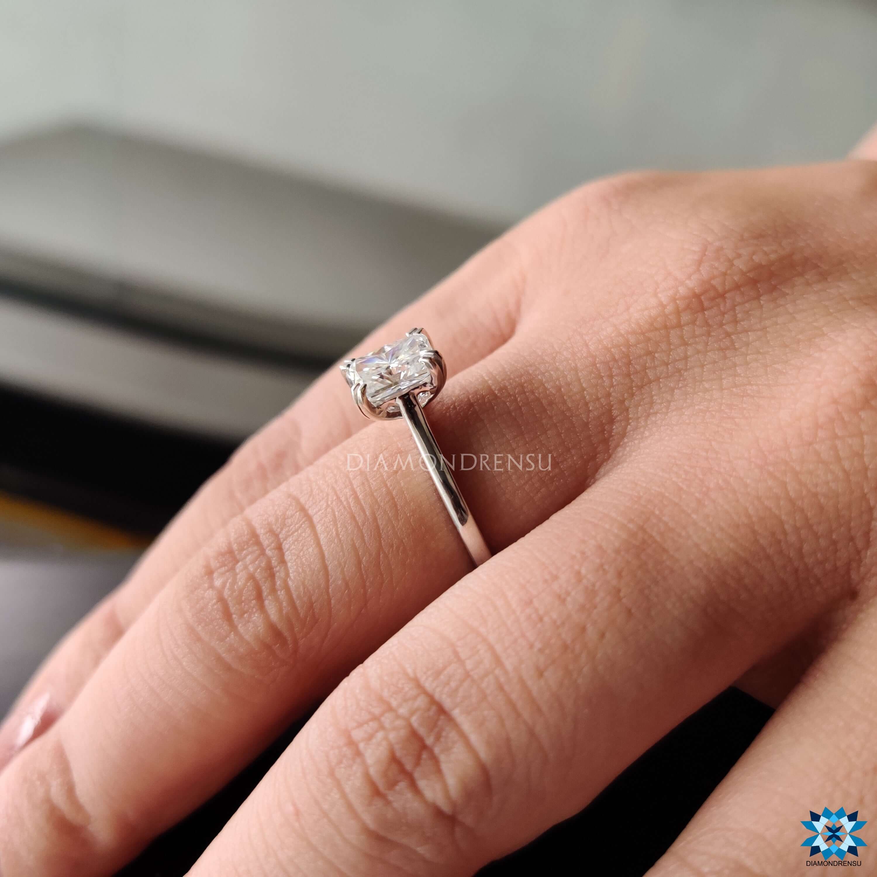 Solitaire moissanite ring featuring radiant cut center stone.