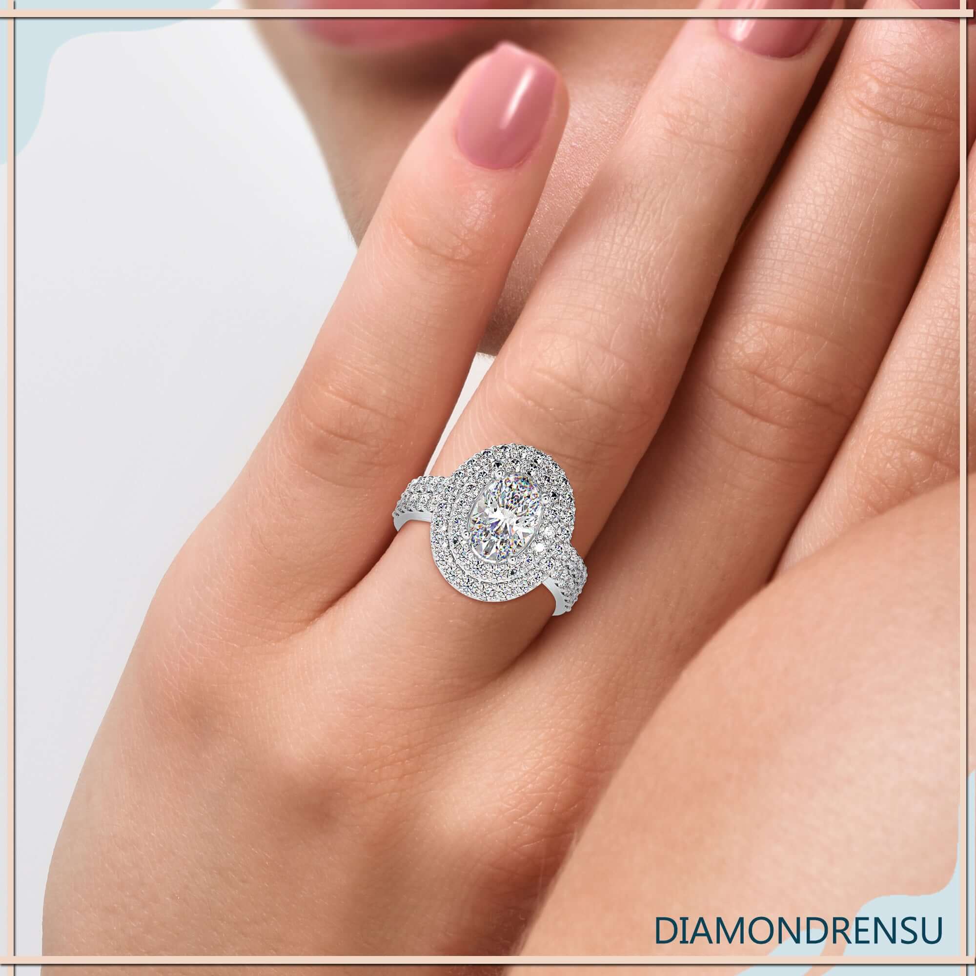 Oval cut diamond centre with double halo and round prong setting.