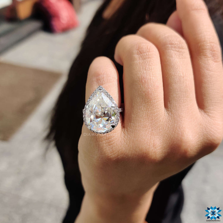 Pave engagement ring with pear cut moissanite and side halo detailing.