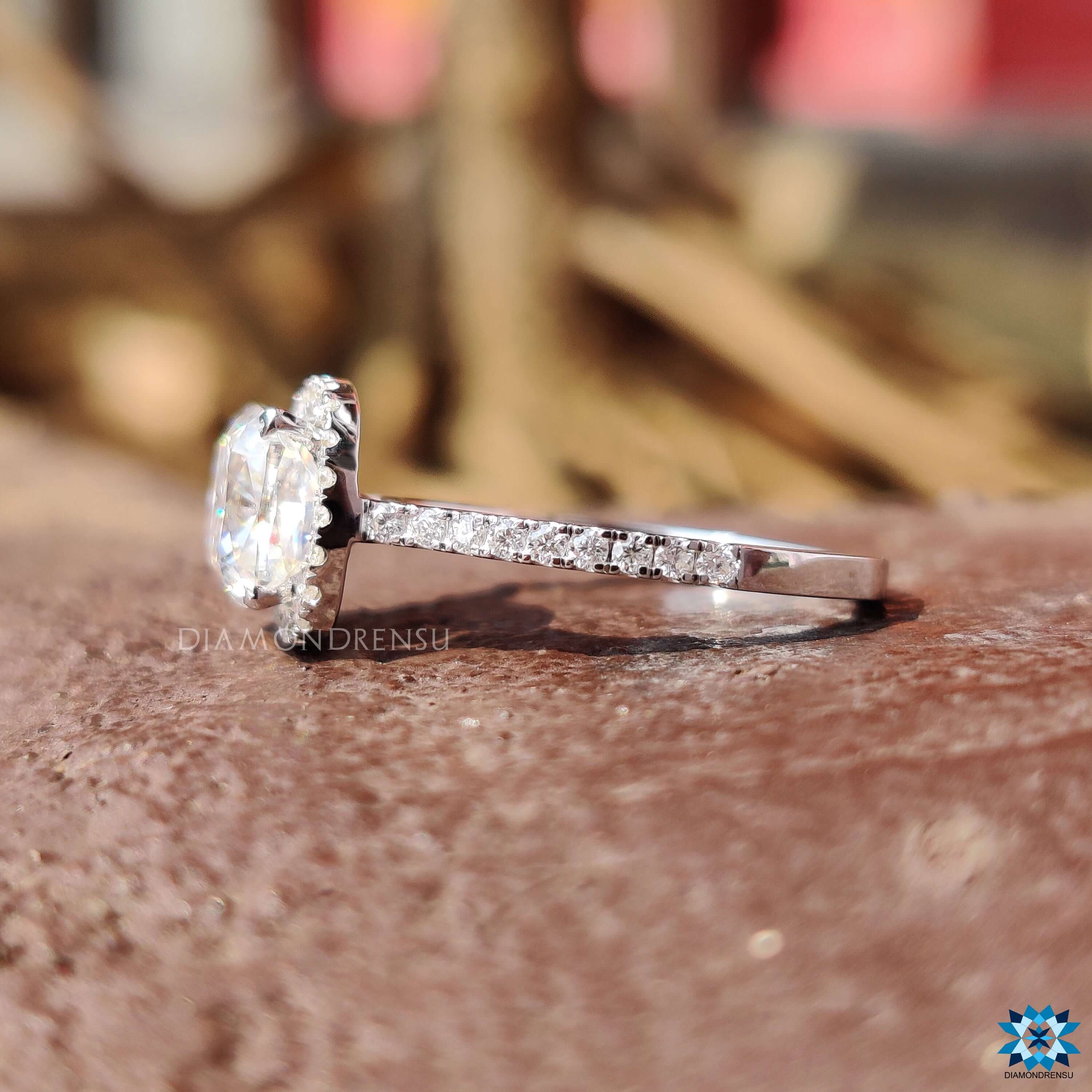 Cushion cut engagement ring with round side stones in pave setting.