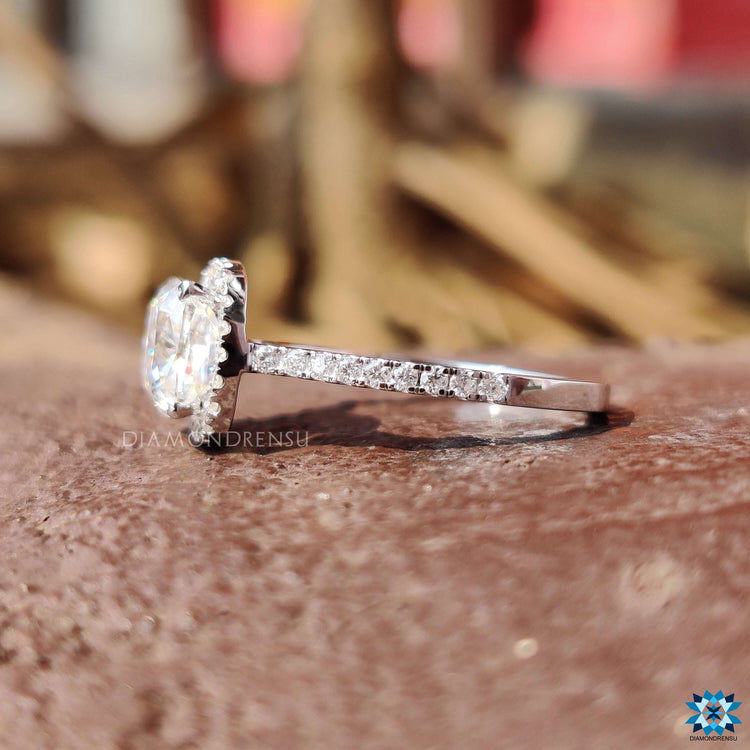 Cushion cut engagement ring with round side stones in pave setting.