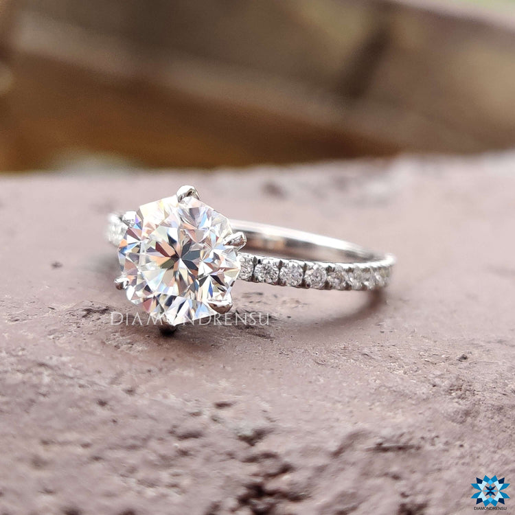 Moissanite ring with round cut pave band and claw prong setting.