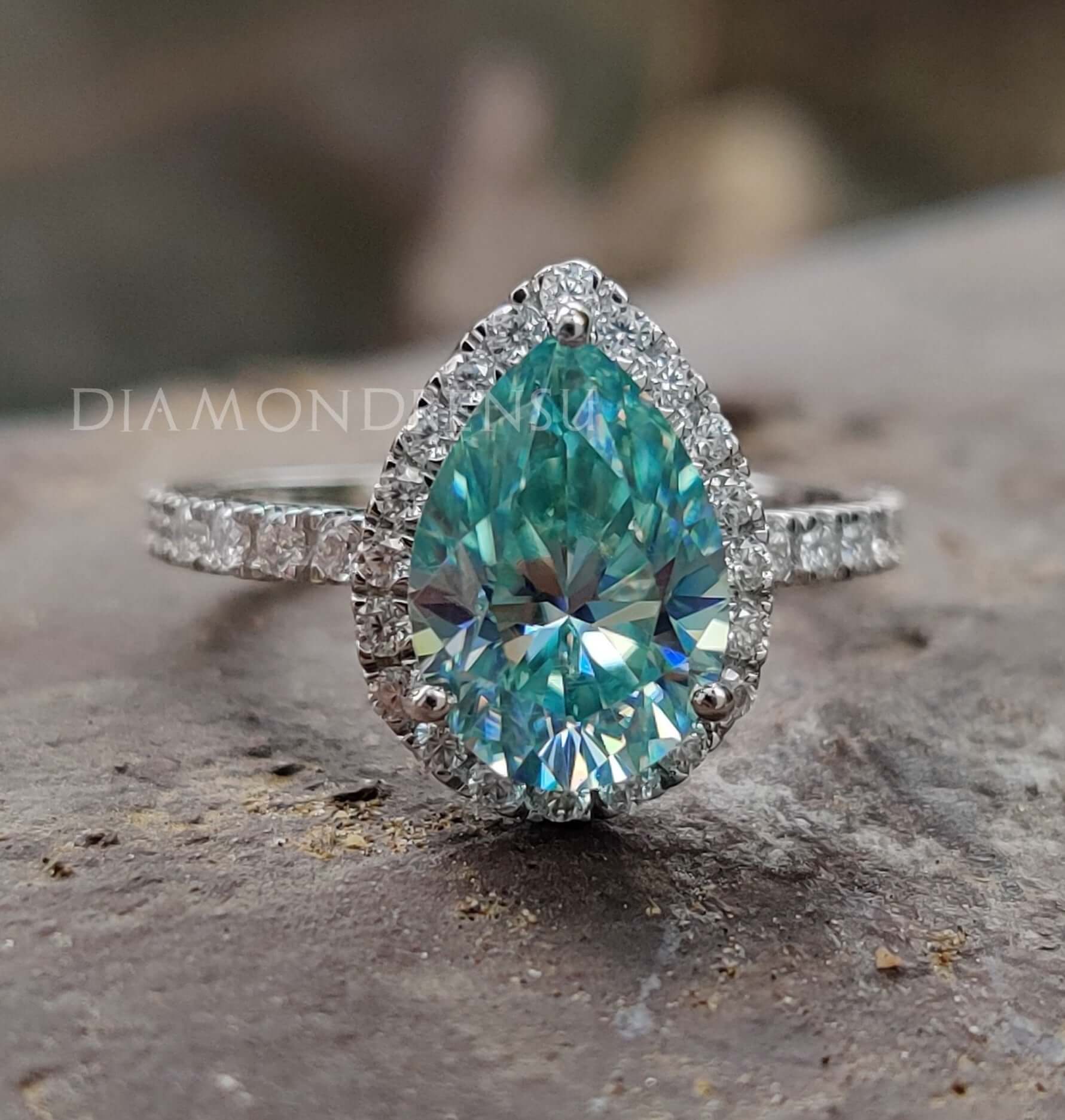 Pear shaped engagement ring with cyan blue moissanite centre stone in white gold band.