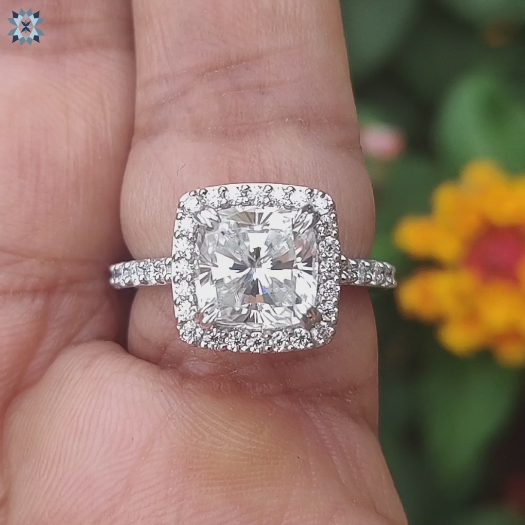 Halo engagement ring with cushion cut moissanite and pavé design.