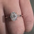 Round cut halo ring featuring claw prong ring setting.