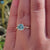 Twisted band engagement ring with hidden halo and round stone.