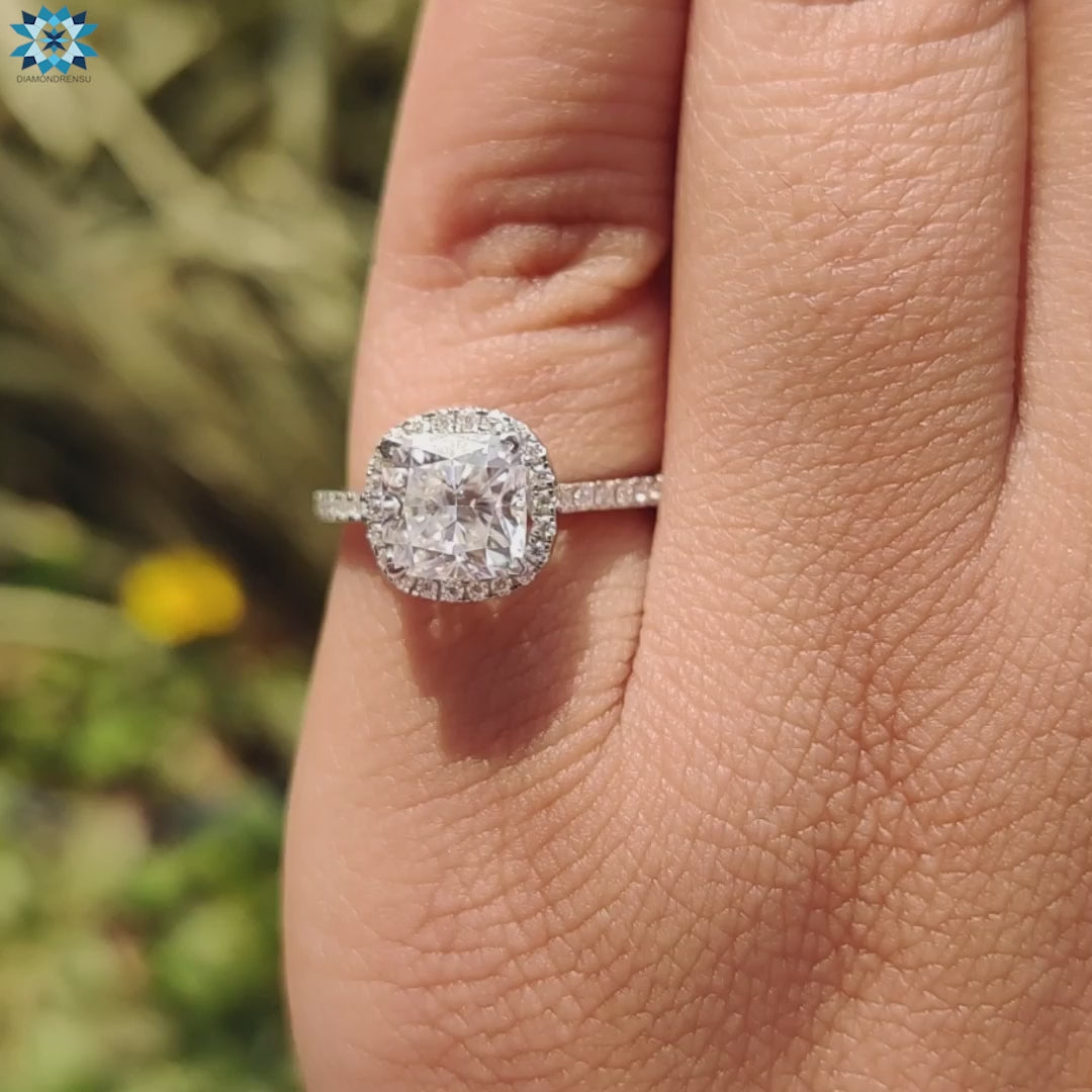 Round brilliant side stones enhance this cushion halo engagement ring.