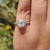Round brilliant side stones enhance this cushion halo engagement ring.