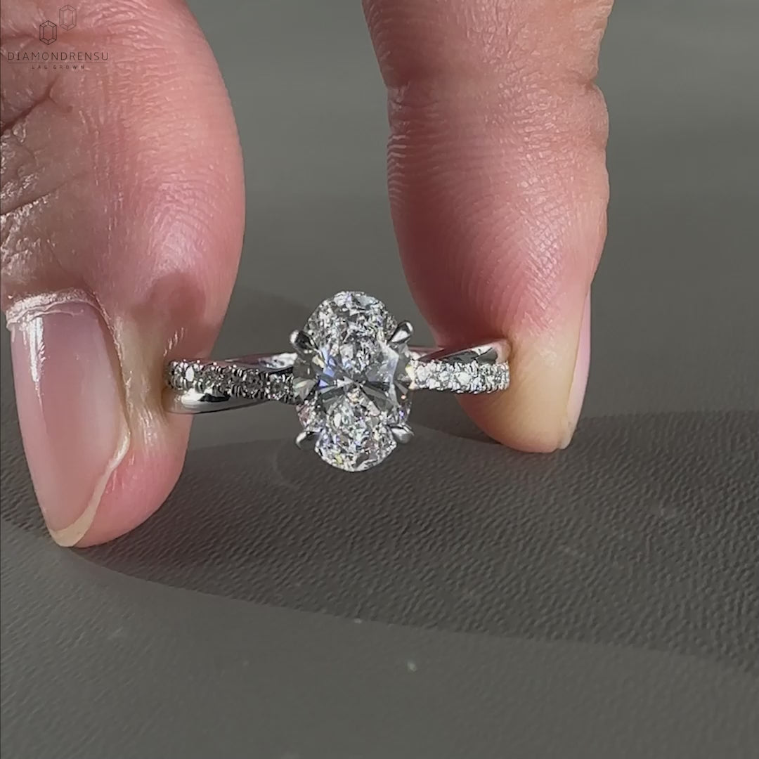 Engagement ring for women featuring a twist engagement ring design with pave ring diamond accents and a 4 prong claw setting.