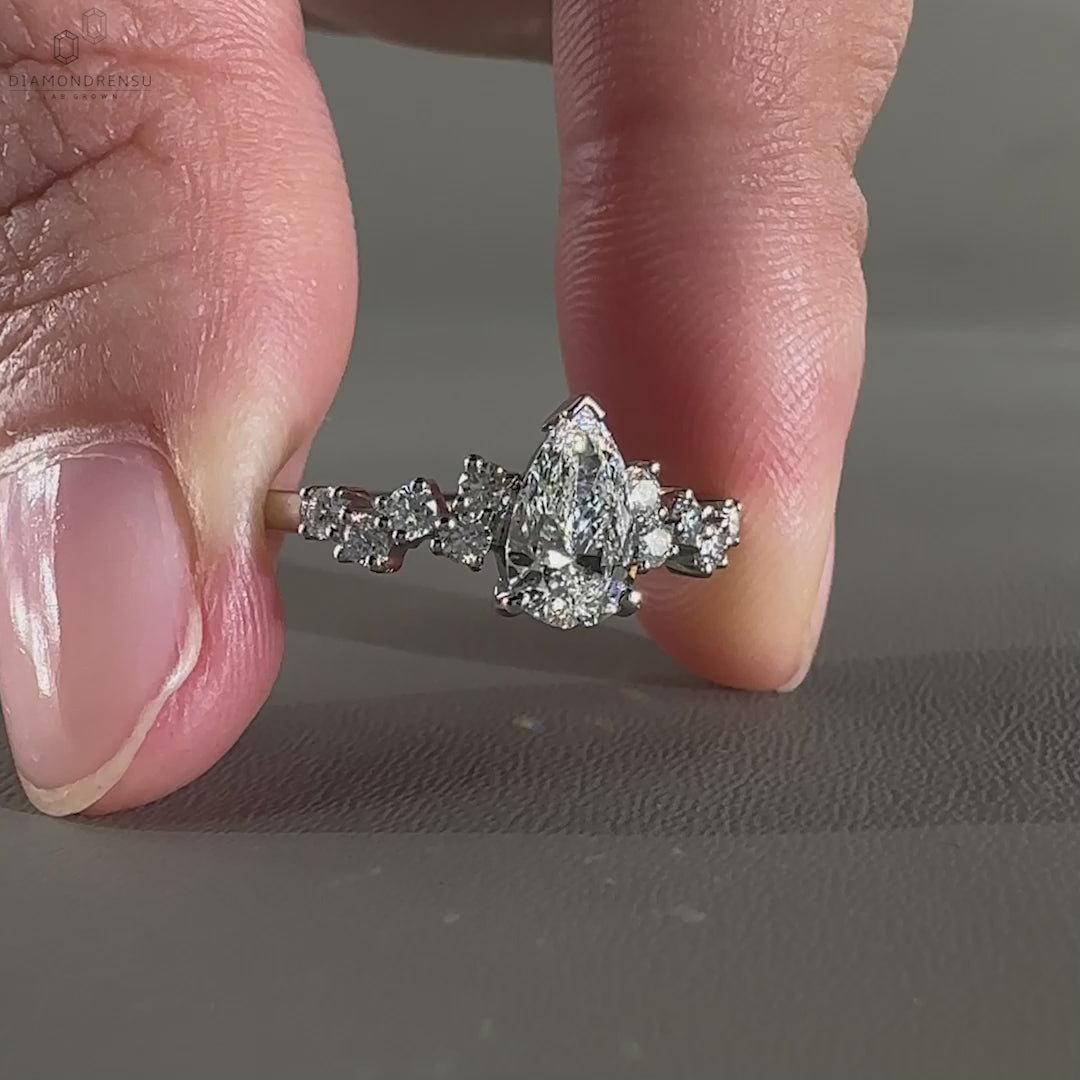 Diamond ring UK featuring a pear cut diamond with round side stones, crafted for a modern and elegant design.