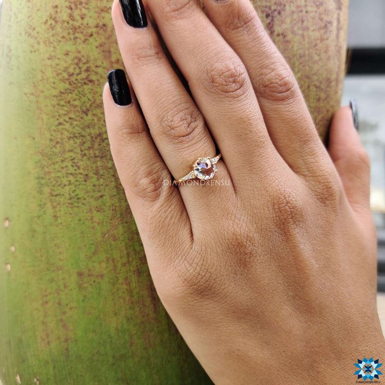 Moissanite engagement ring in yellow gold with muse setting and side stones.