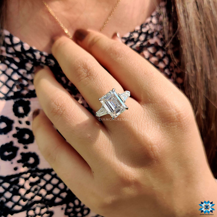 Three stone emerald cut engagement ring with bullet shaped side stones.