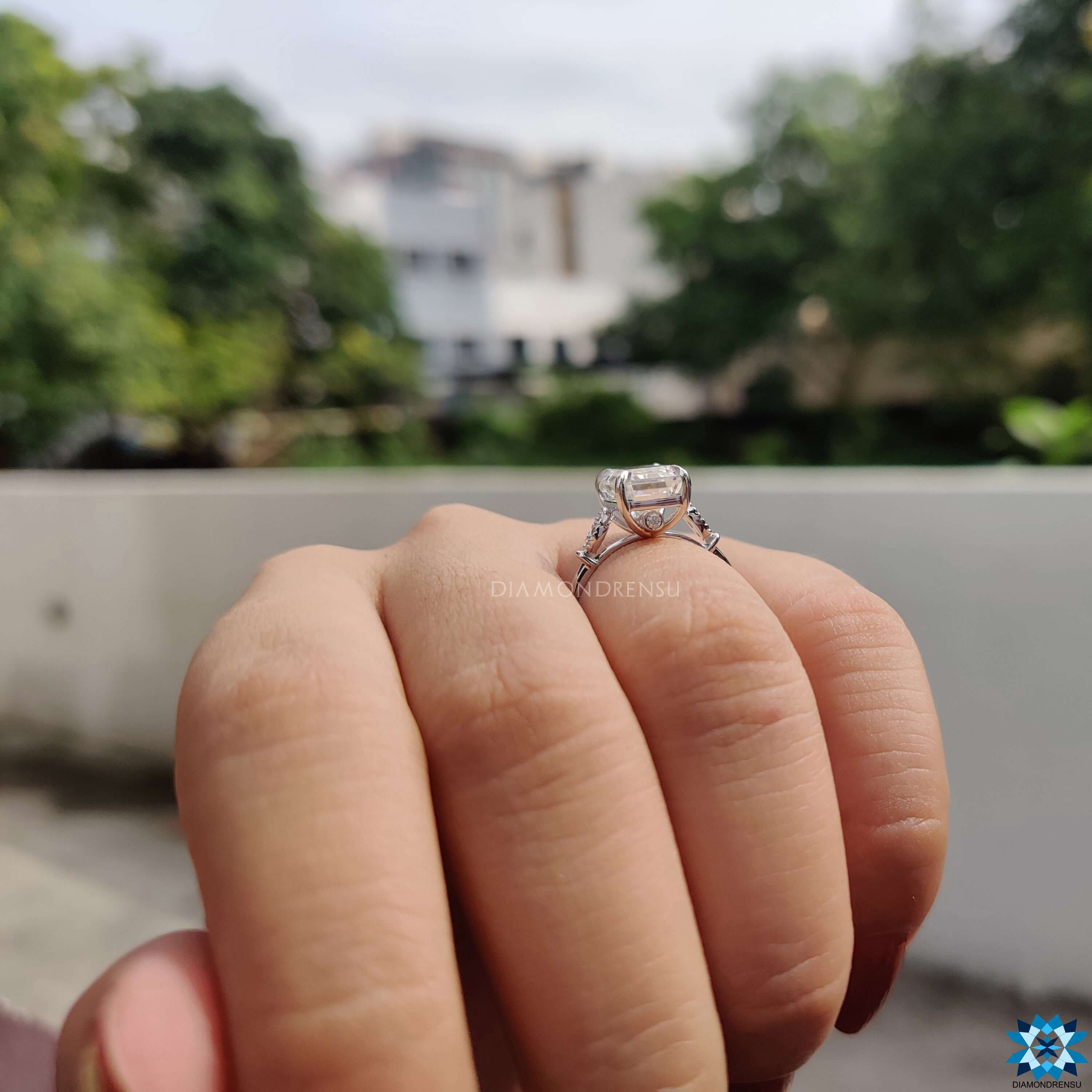 Moissanite engagement ring with round side stones and milgrain edges.