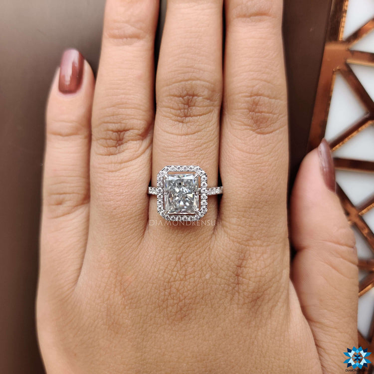 White gold ring with a radiant cut moissanite and halo of round diamonds.