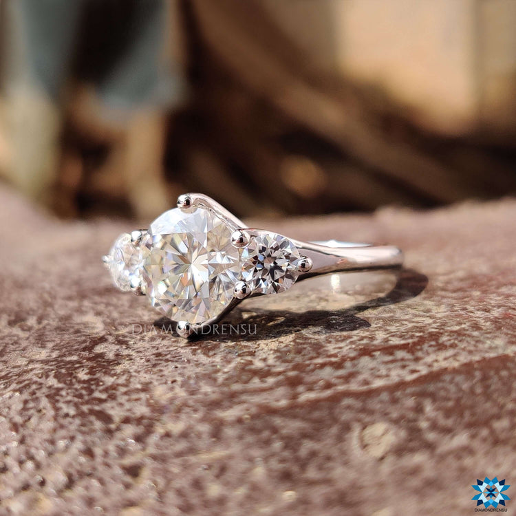 Round moissanite engagement ring with triple stone layout.