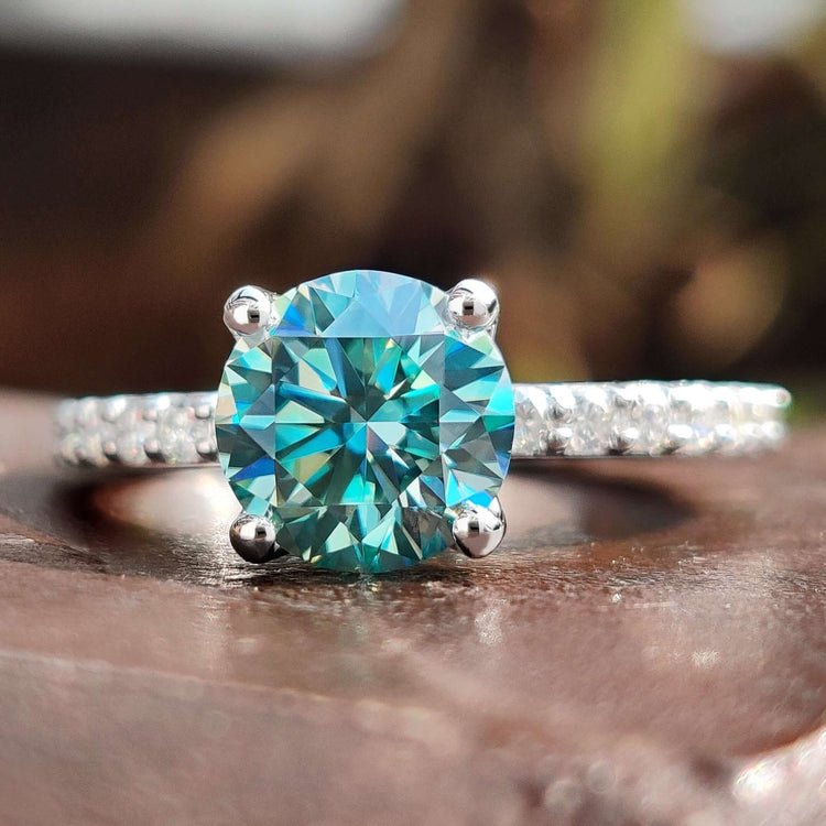 Round cut engagement ring with cyan blue moissanite.