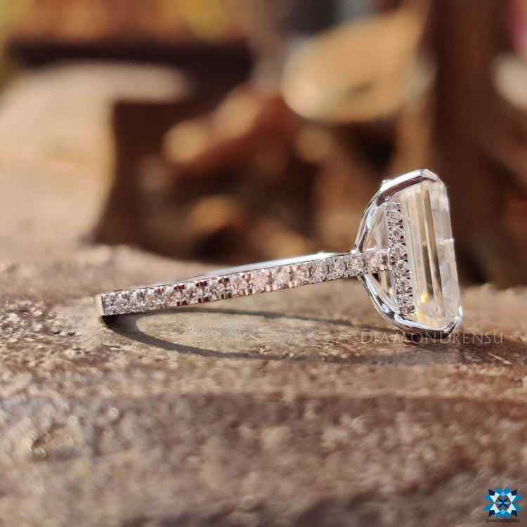 Moissanite hidden halo ring with emerald cut center and 4 claw prongs.