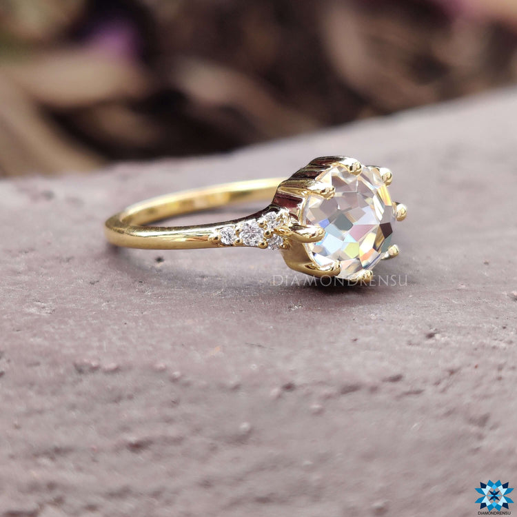 Yellow gold ring featuring a round rose cut moissanite and side stones.